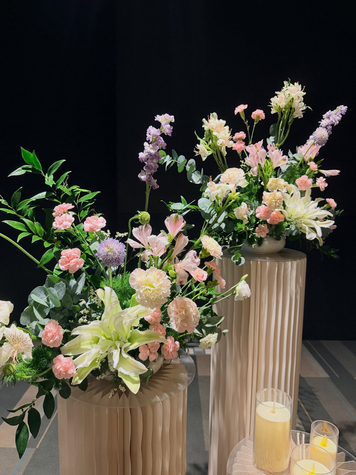 A tall pastel pedestal arrangement in pink, peach and white by Bespoke Blooms